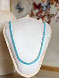 Turquoise beaded necklace on a mannequin bust with a decorative butterfly background.