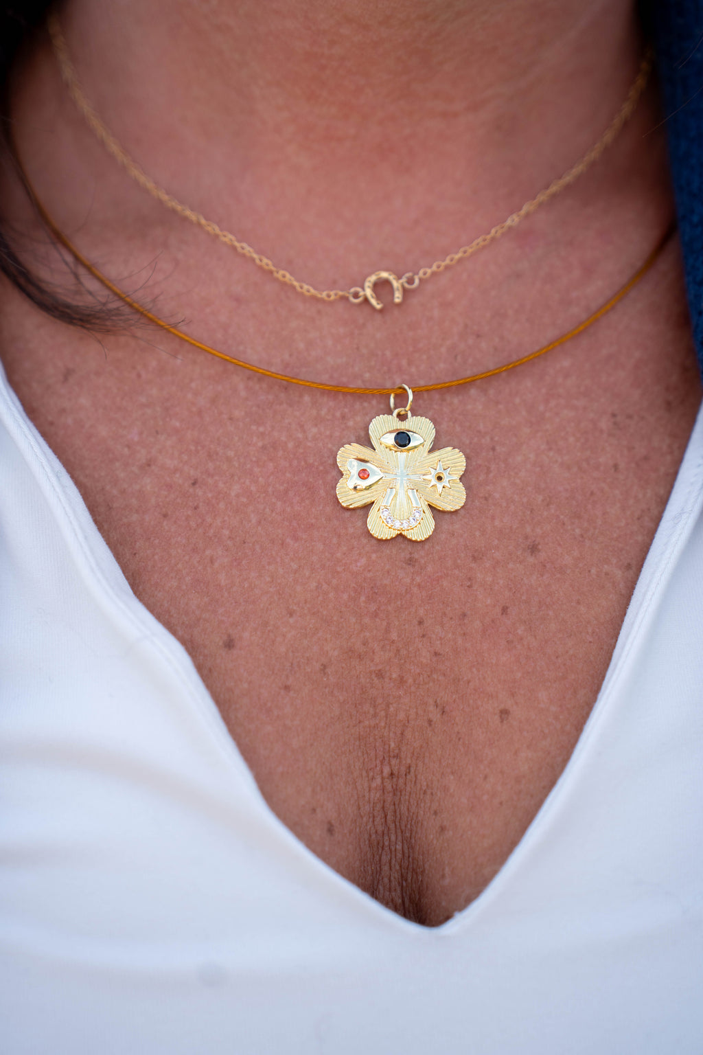 A close-up of a person's neck and chest wearing two layered necklaces. The top necklace is a delicate gold chain with a small crescent moon pendant.